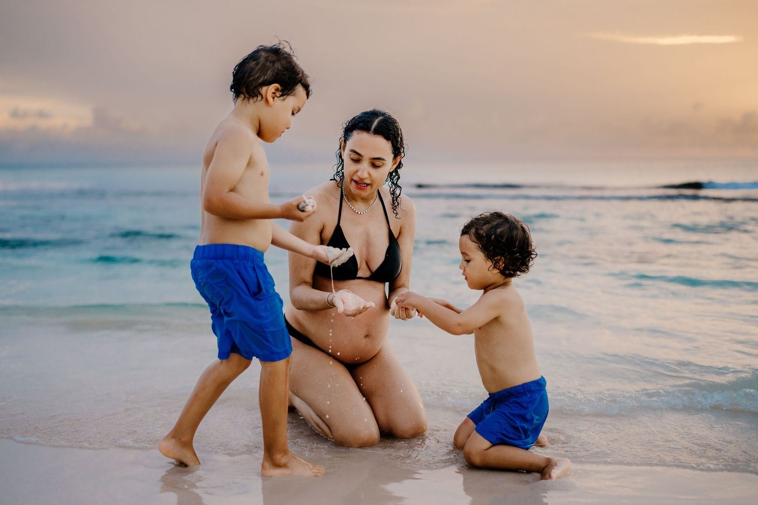 Family playing together in the gentle ocean waves at sunset.