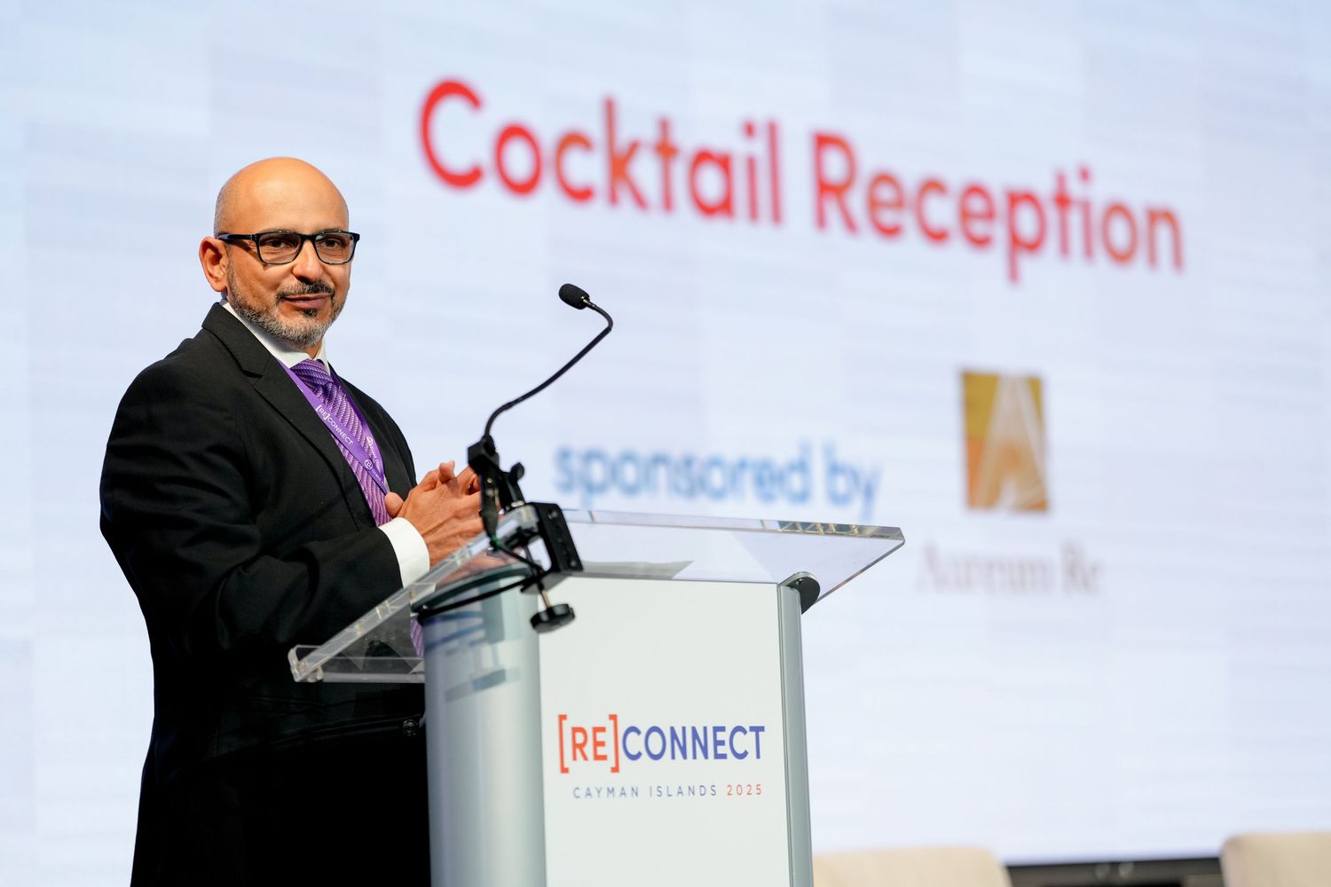 A speaker presents at a podium during a cocktail reception event.