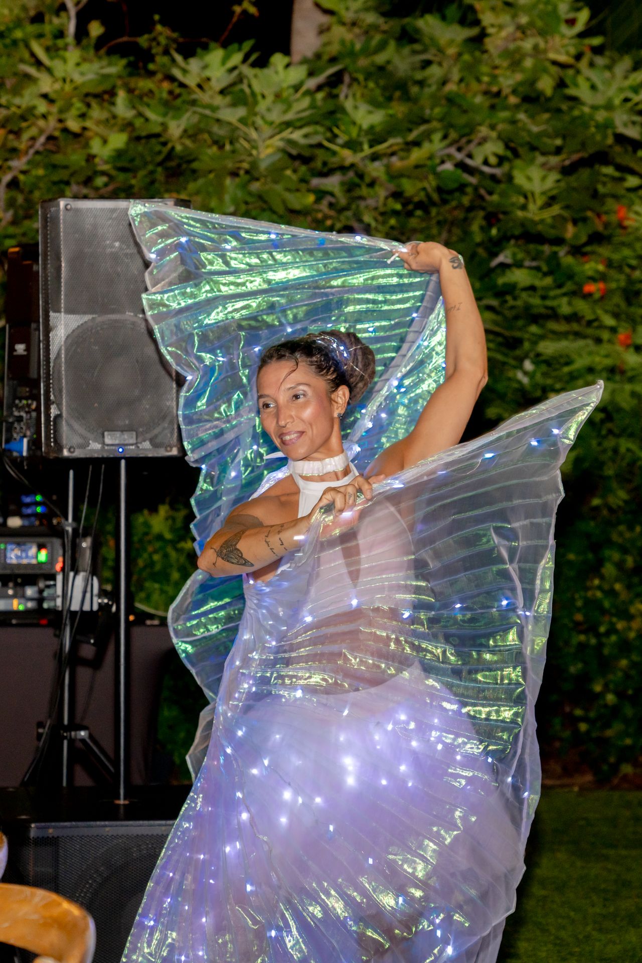 Dancer performing with an iridescent fabric creating a magical light effect outdoors.