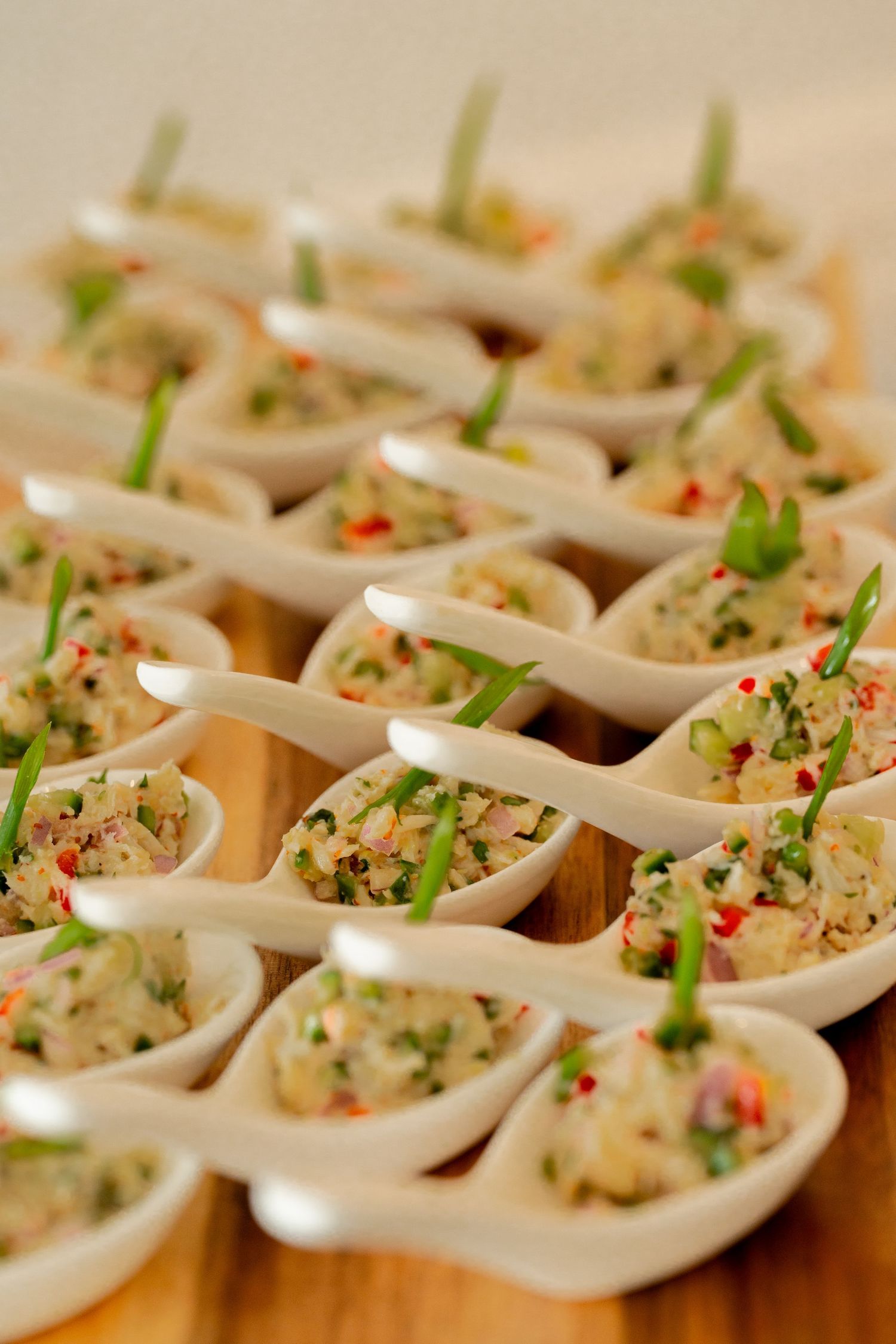 Elegant appetizers served in white ceramic spoons garnished with herbs and spices.