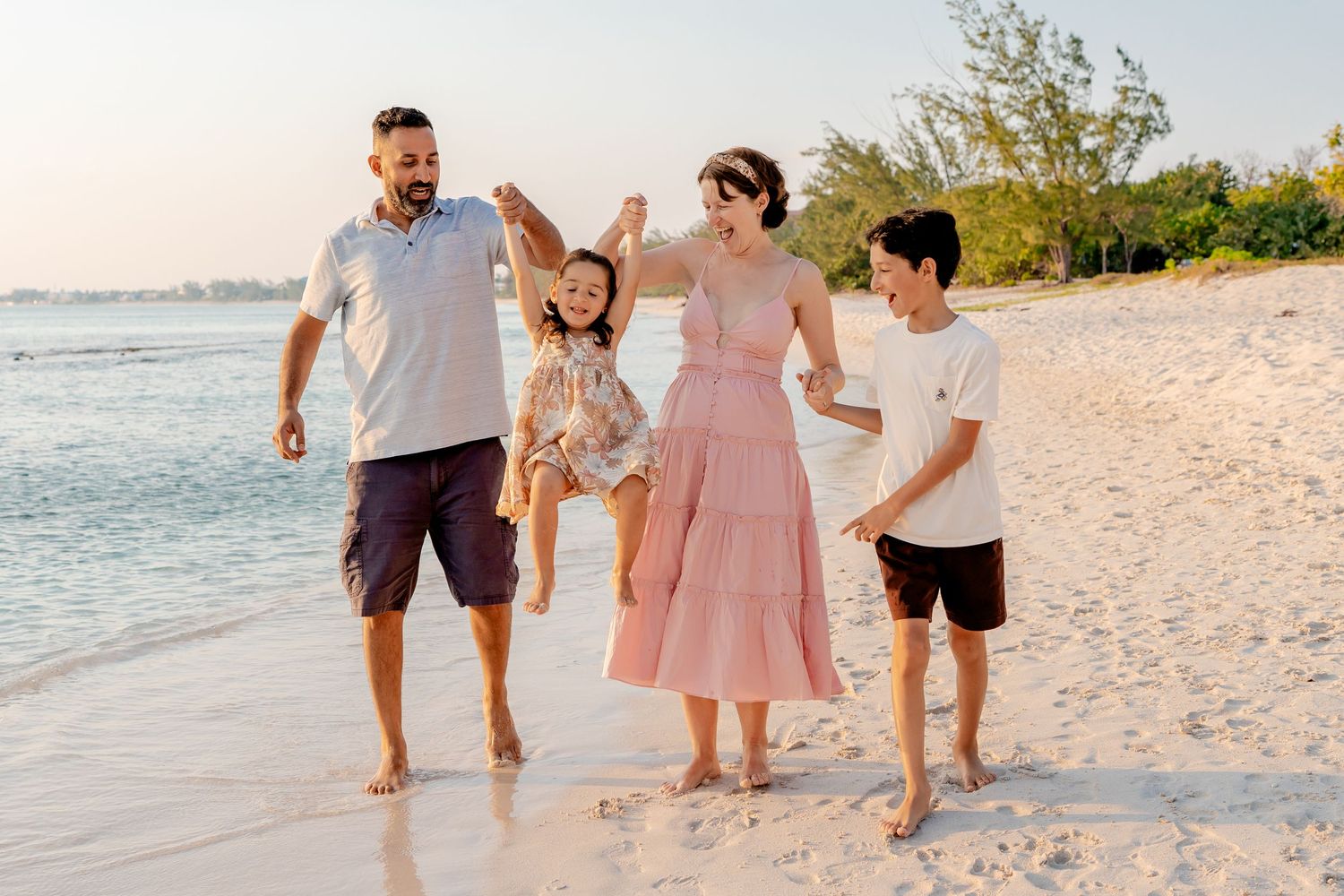 A joyful family moment captured while walking along the shoreline at sunset.