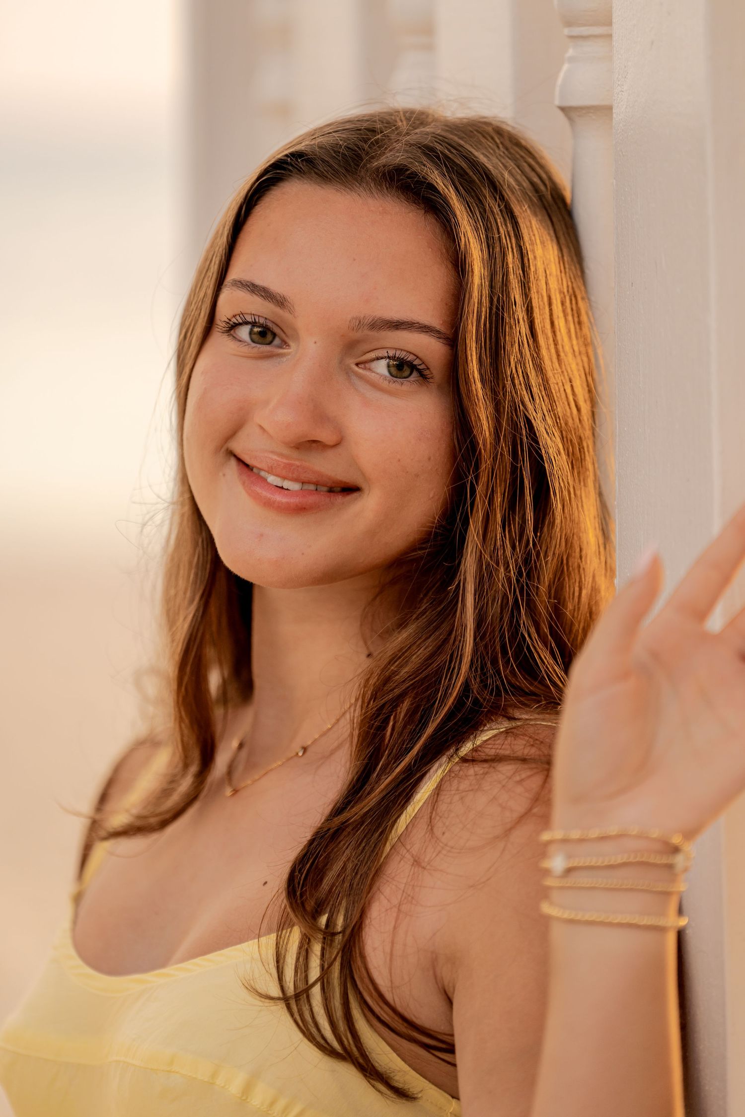 Portrait of woman in yellow top with long brown hair and natural makeup.