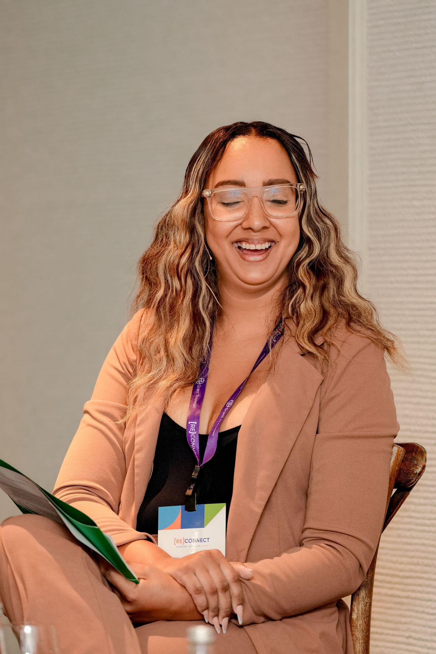 Professional in a beige blazer smiling while participating in a business meeting.