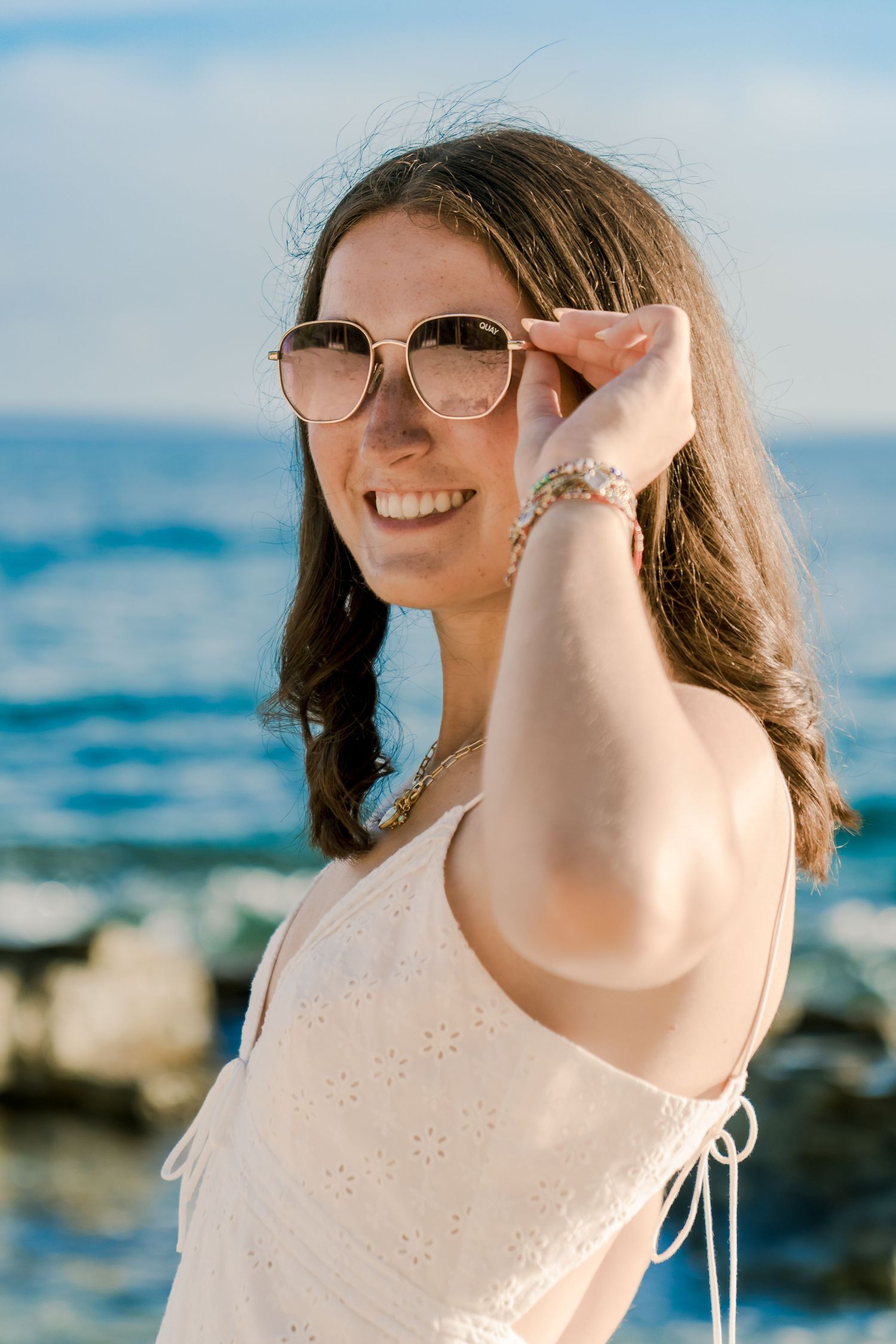 Candid portraits by the ocean showing joyful expressions and sunlit scenery.