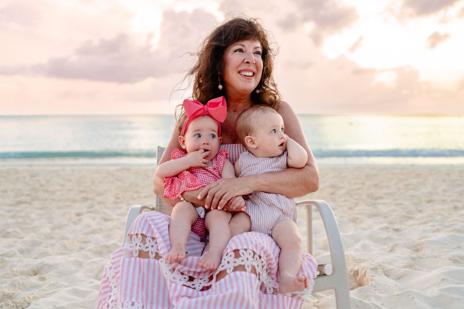 Family enjoying a playful moment together on a beautiful beach at sunset with turquoise waters and soft sand.