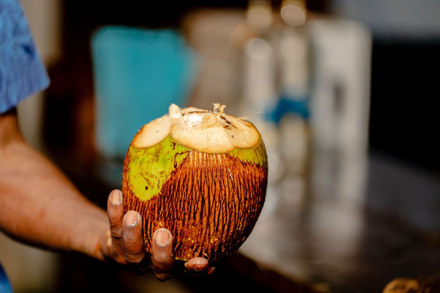 Tropical drinks served in fresh coconuts with garnishes at a beach bar.