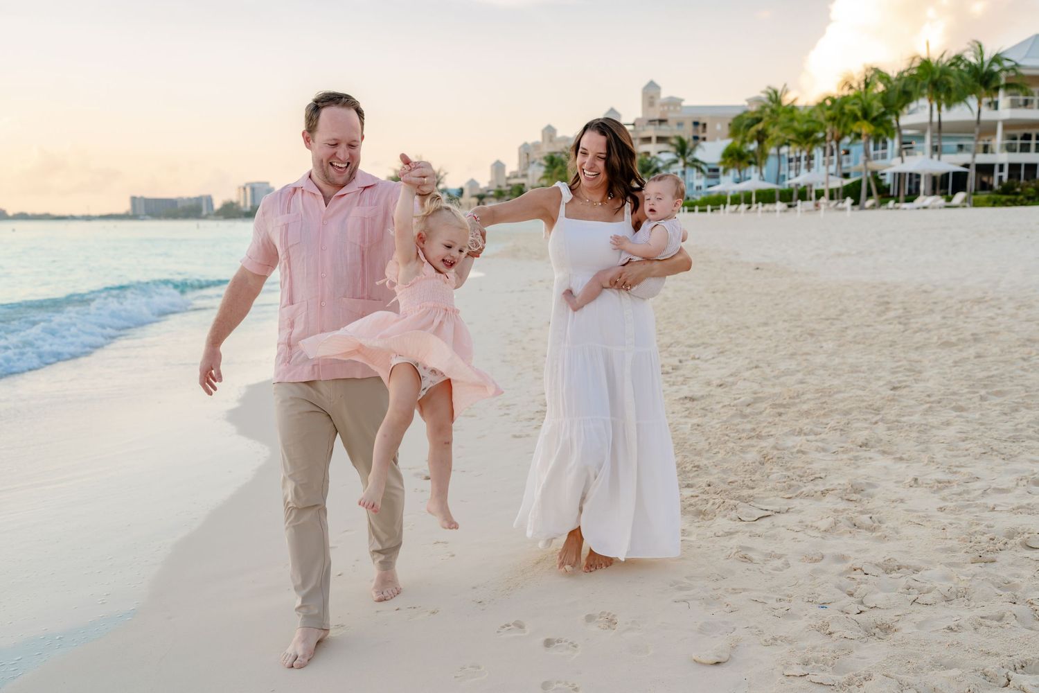 Family playing and running together on a pristine beach at dusk.