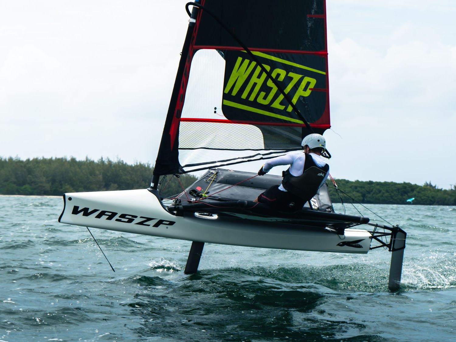 WASZP hydrofoil sailboat gliding above water with sailor on board on a calm day.