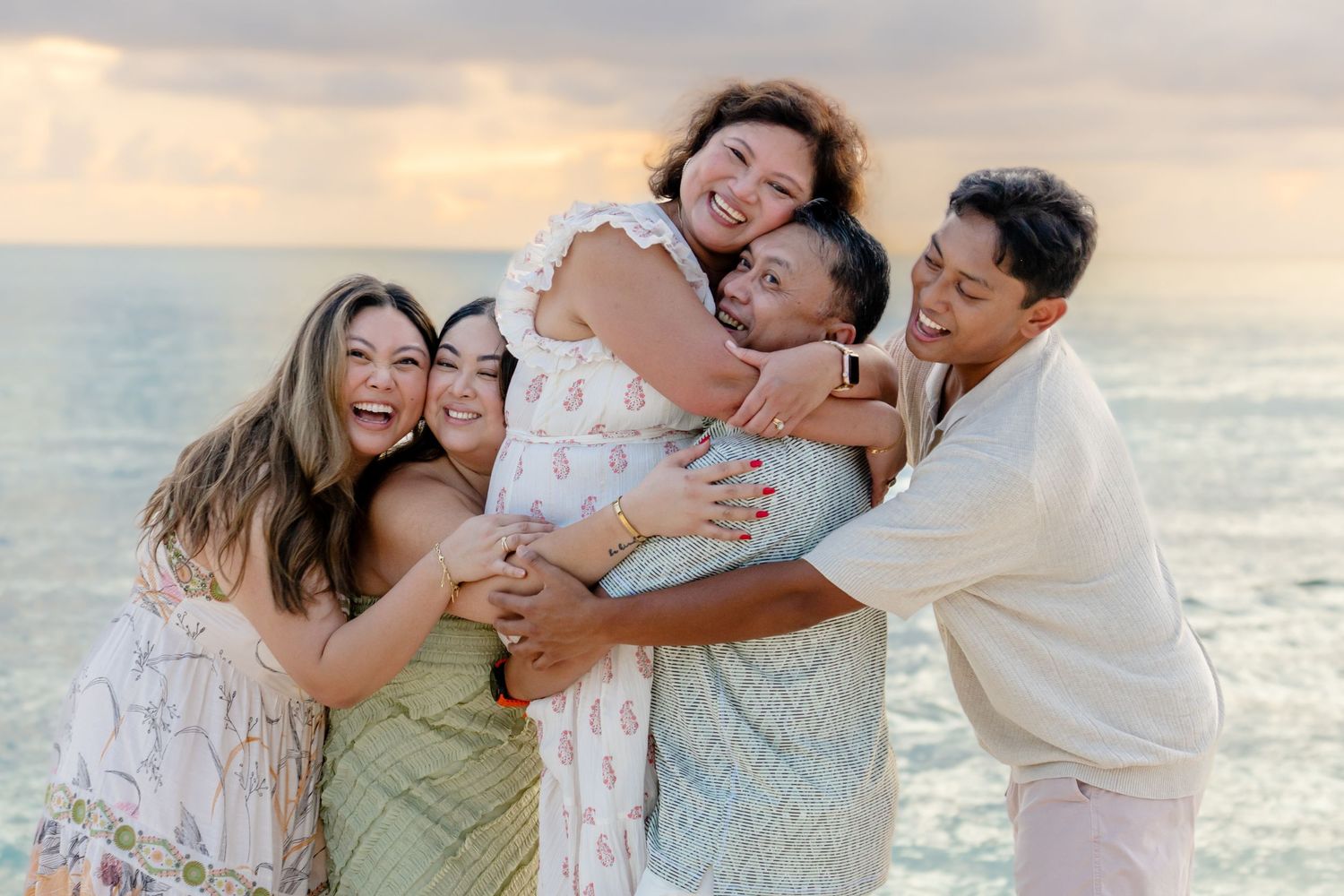 Joyful group hug captured on beach during golden hour.
