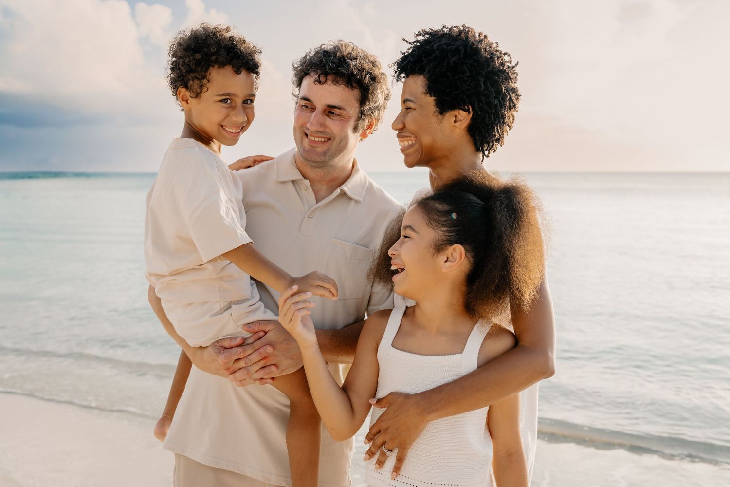 Family shares joyful moments together on a sunny beach with ocean views.