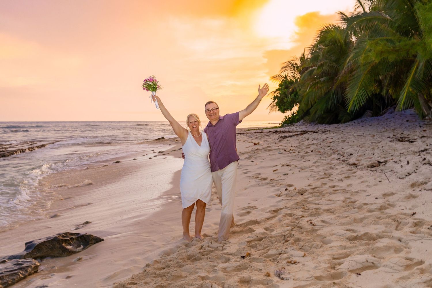 Romantic beach photography session during a vibrant orange sunset.