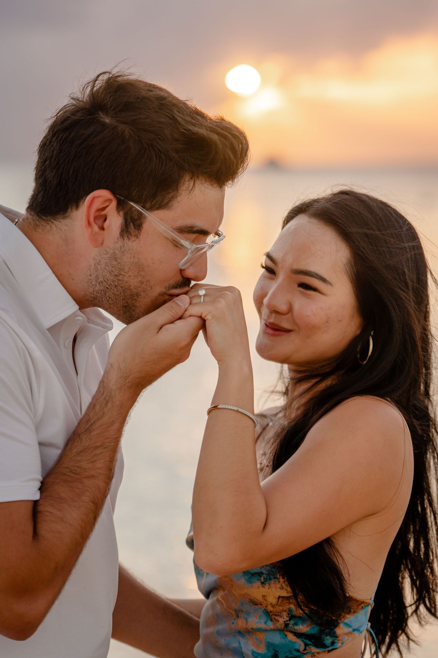Couple sharing intimate moments during a beach sunset photoshoot.