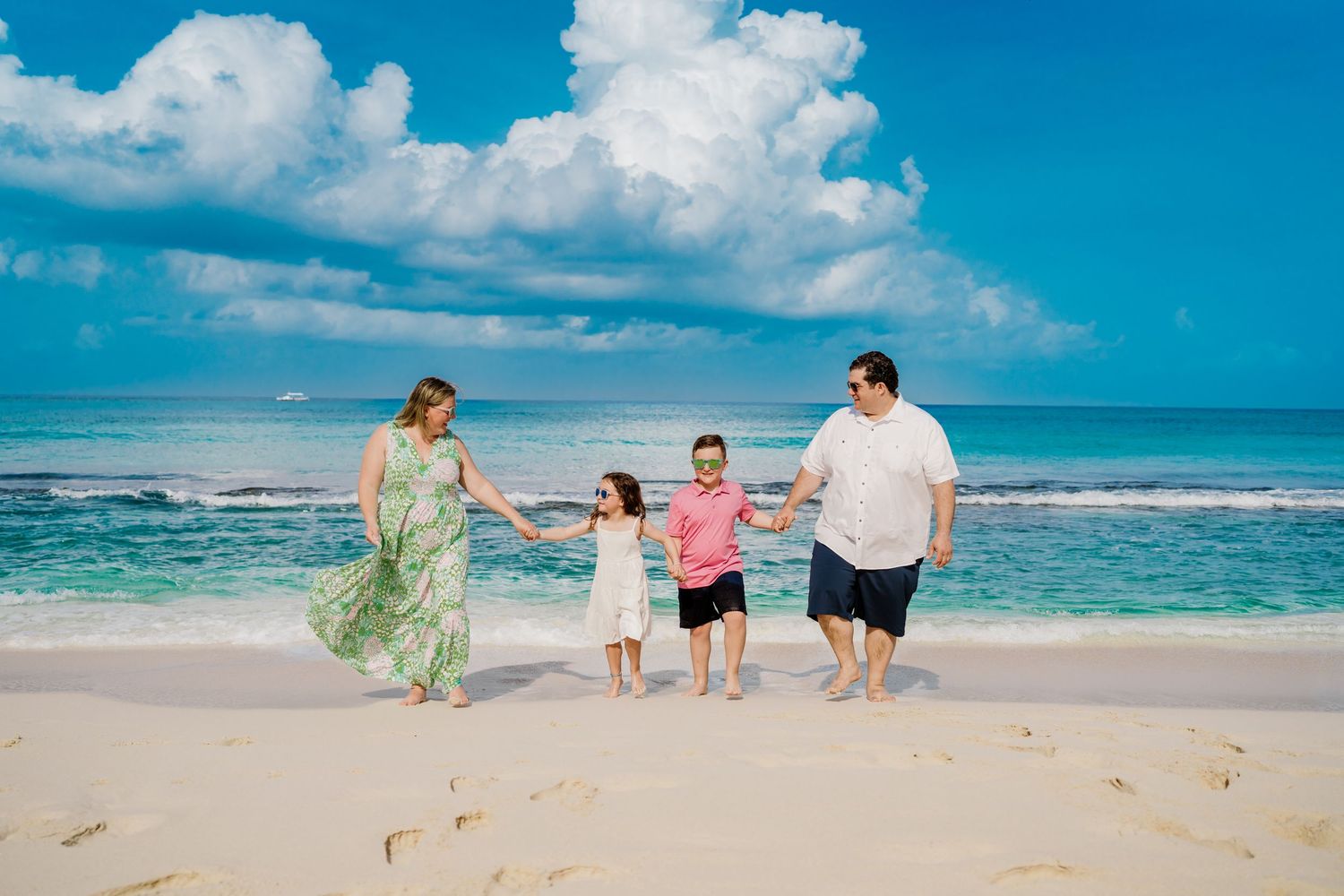 Group walking together on pristine beach with turquoise waters and dramatic cloud formations.