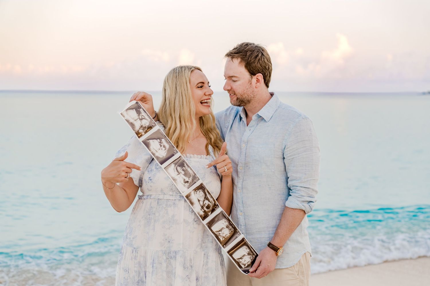 Couple celebrating with champagne on beach at sunset.