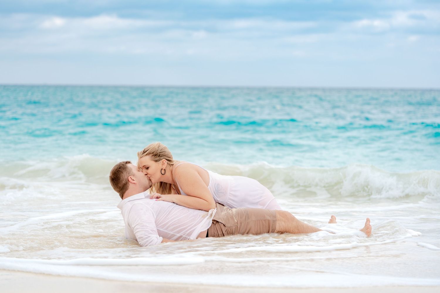 A tender moment shared on the beach as waves gently roll in.