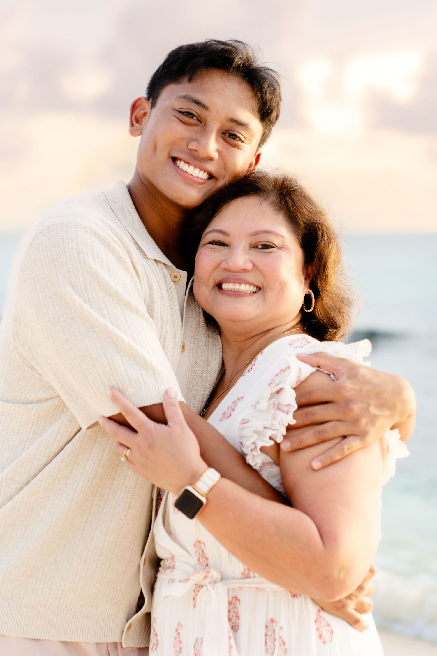 Tender moment captured between two people embracing on beach at sunset.