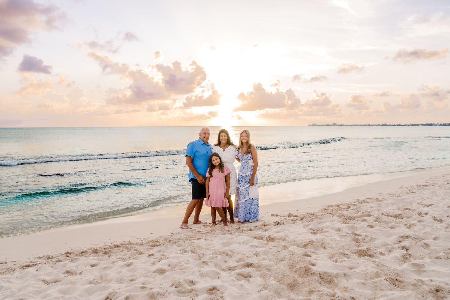 Family silhouettes walk along a peaceful beach shoreline during golden hour.