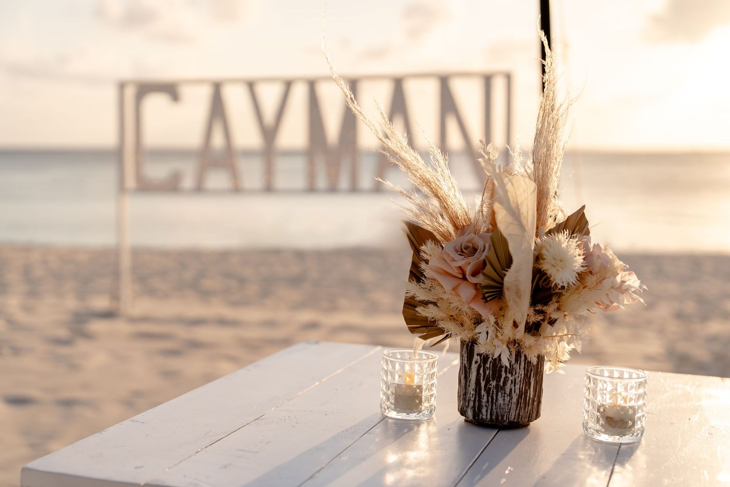Elegant beach wedding table setting with dried palm fronds and neutral decor.