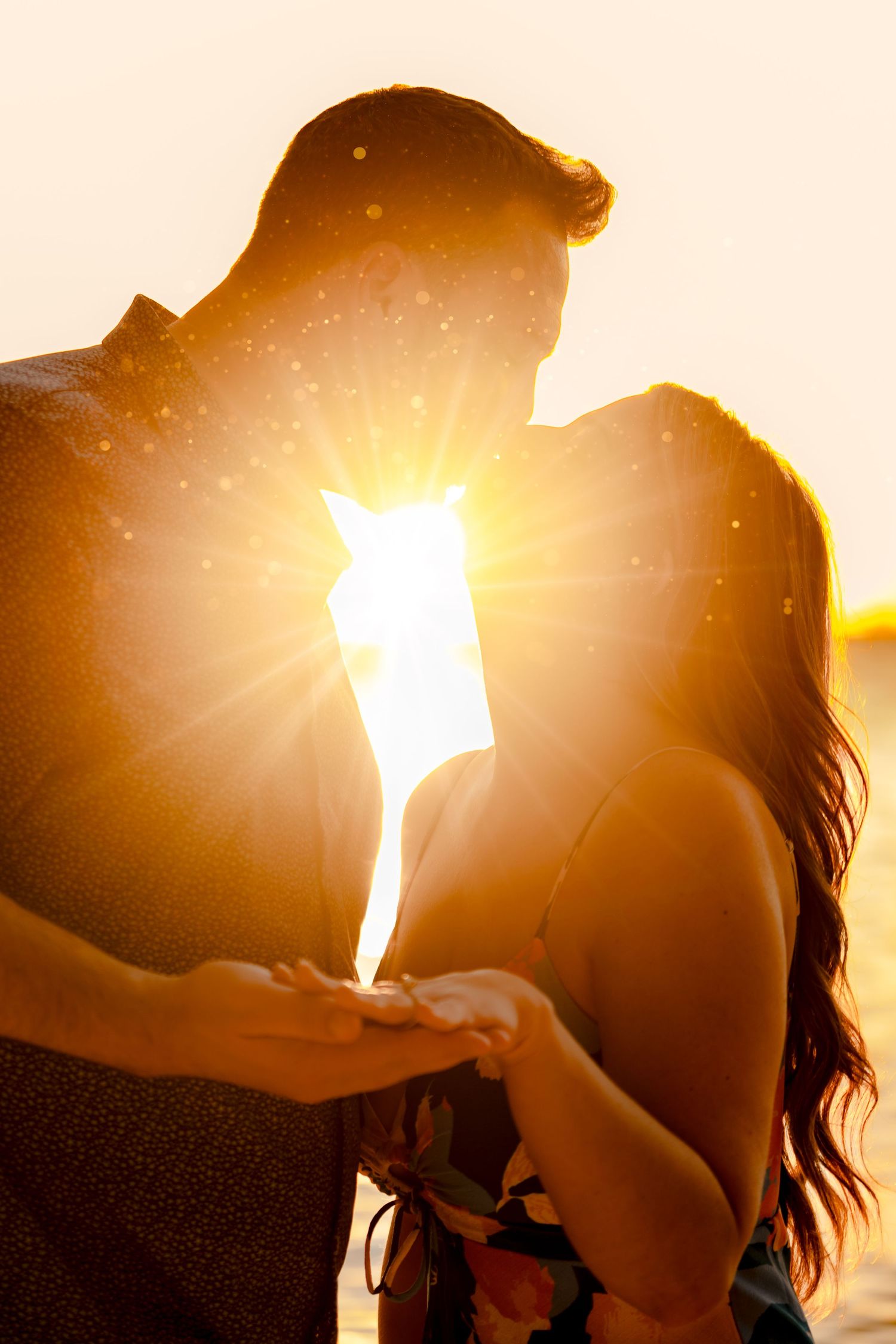 Romantic silhouettes of a couple embracing against a golden sunset on the beach.