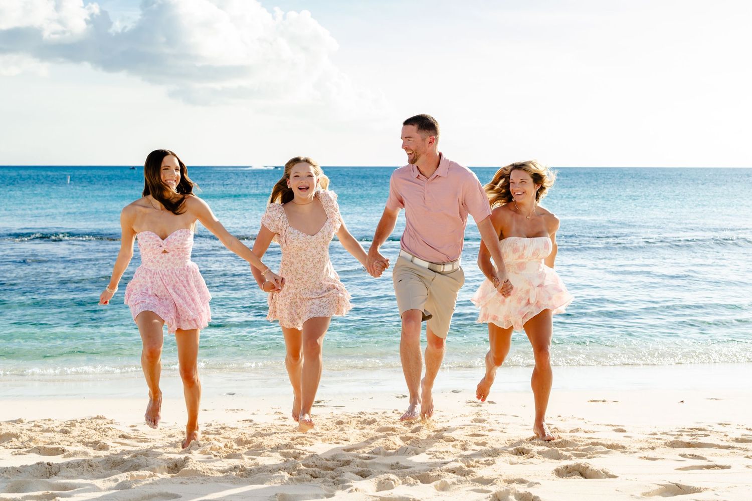 Playful beach photoshoot with family members running and jumping in the sand.