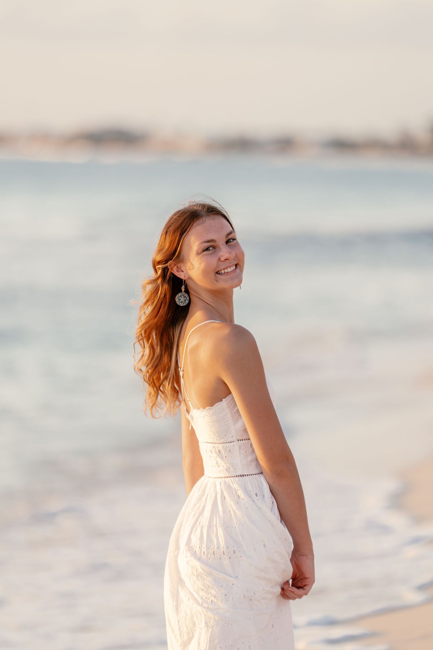 Candid beach portraits showing carefree moments in white sundress.