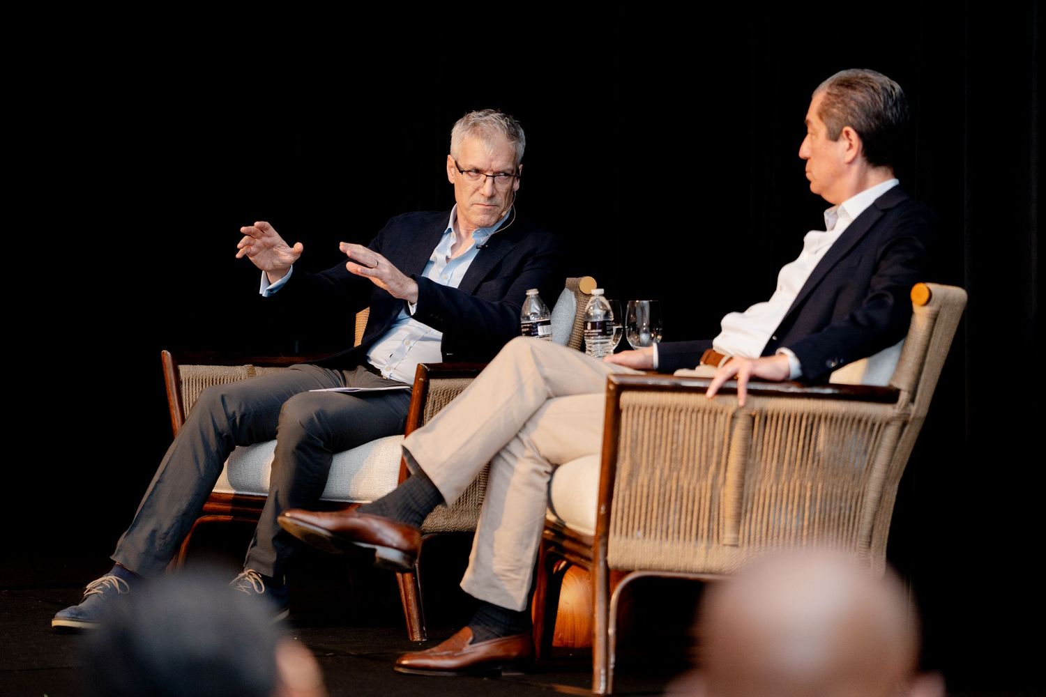Panel discussion setup with speakers seated in comfortable chairs on stage.