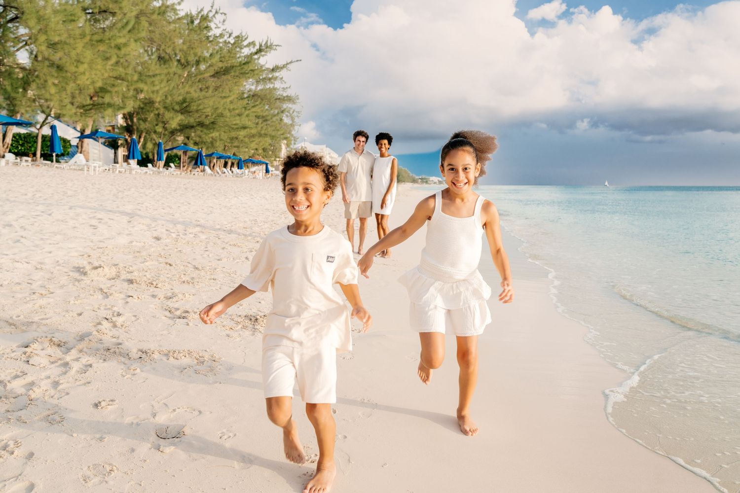 Family members run and play together on a pristine white sand beach.