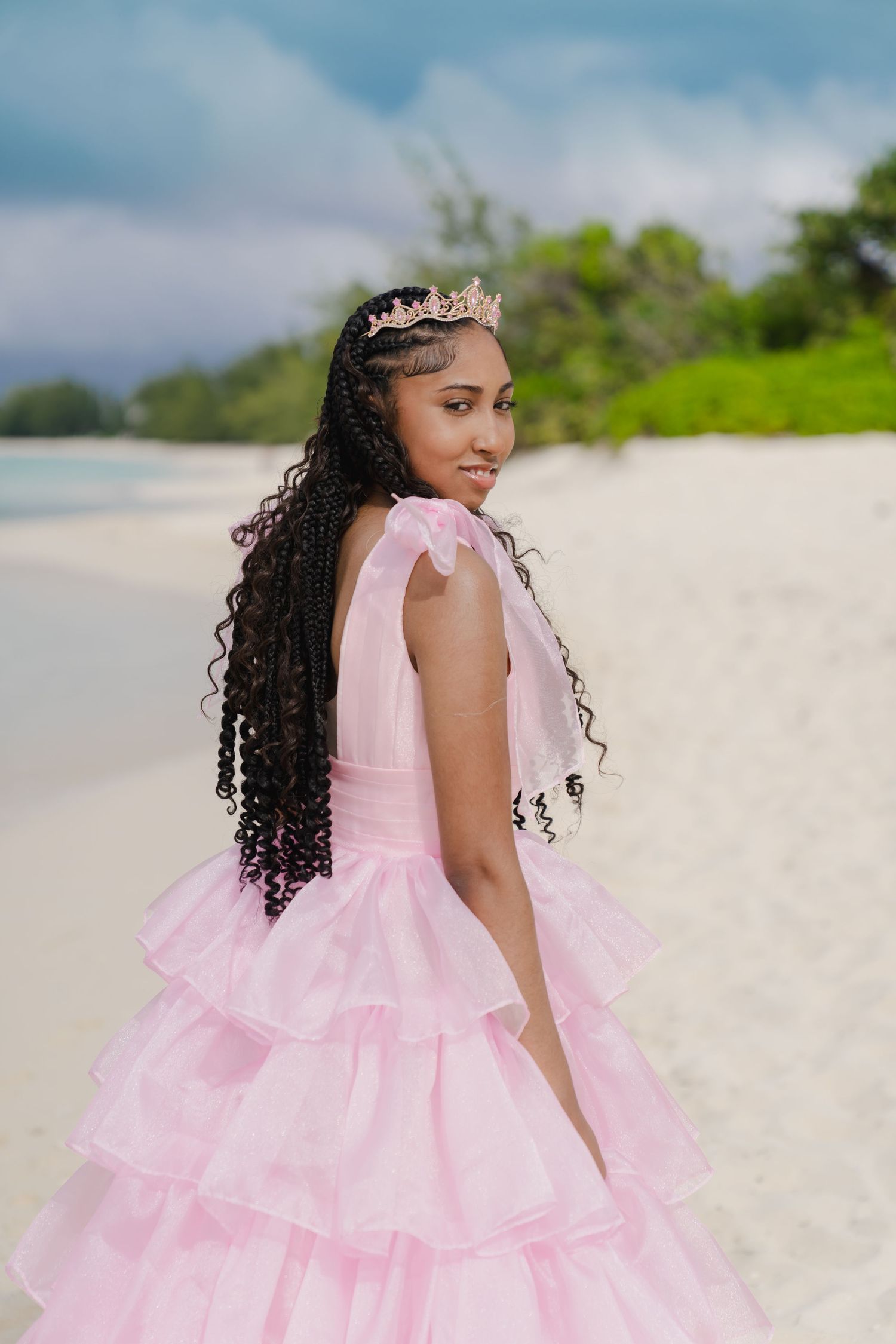 Side view of person in pink princess dress posing on beach.