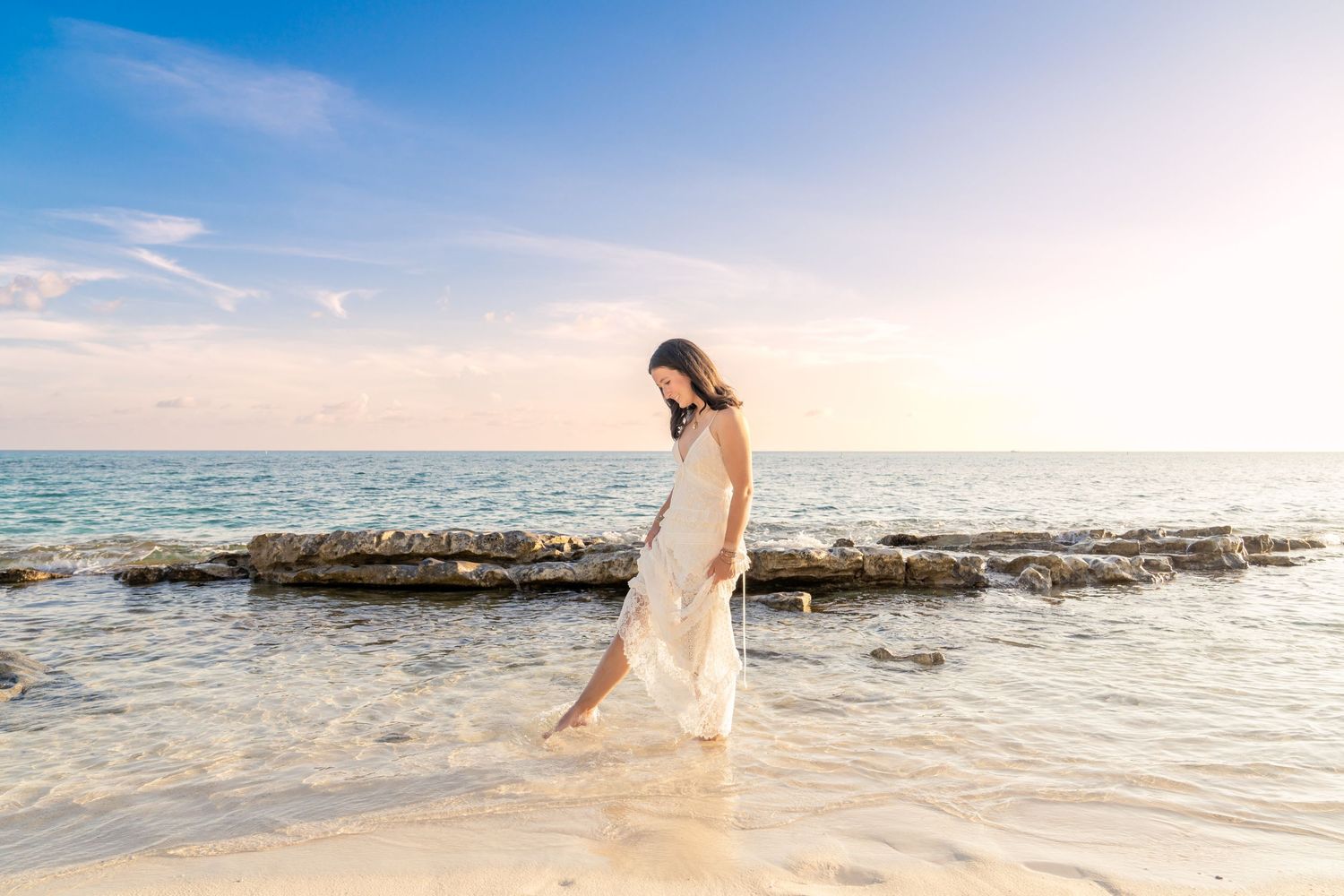 Wide angle beach landscape with rocks and gentle waves at golden hour.