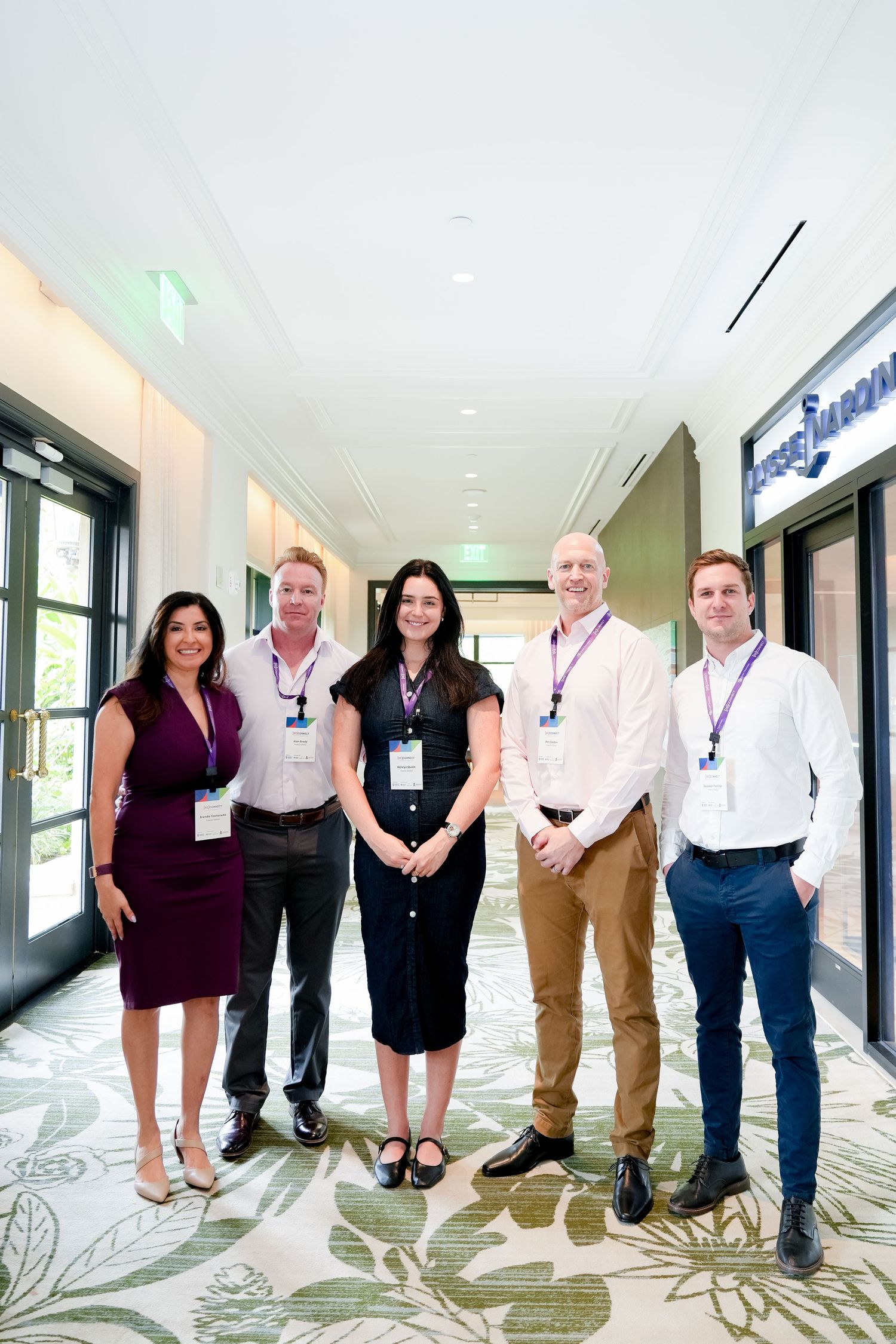 Business professionals lined up against a decorative wall for a group photo.