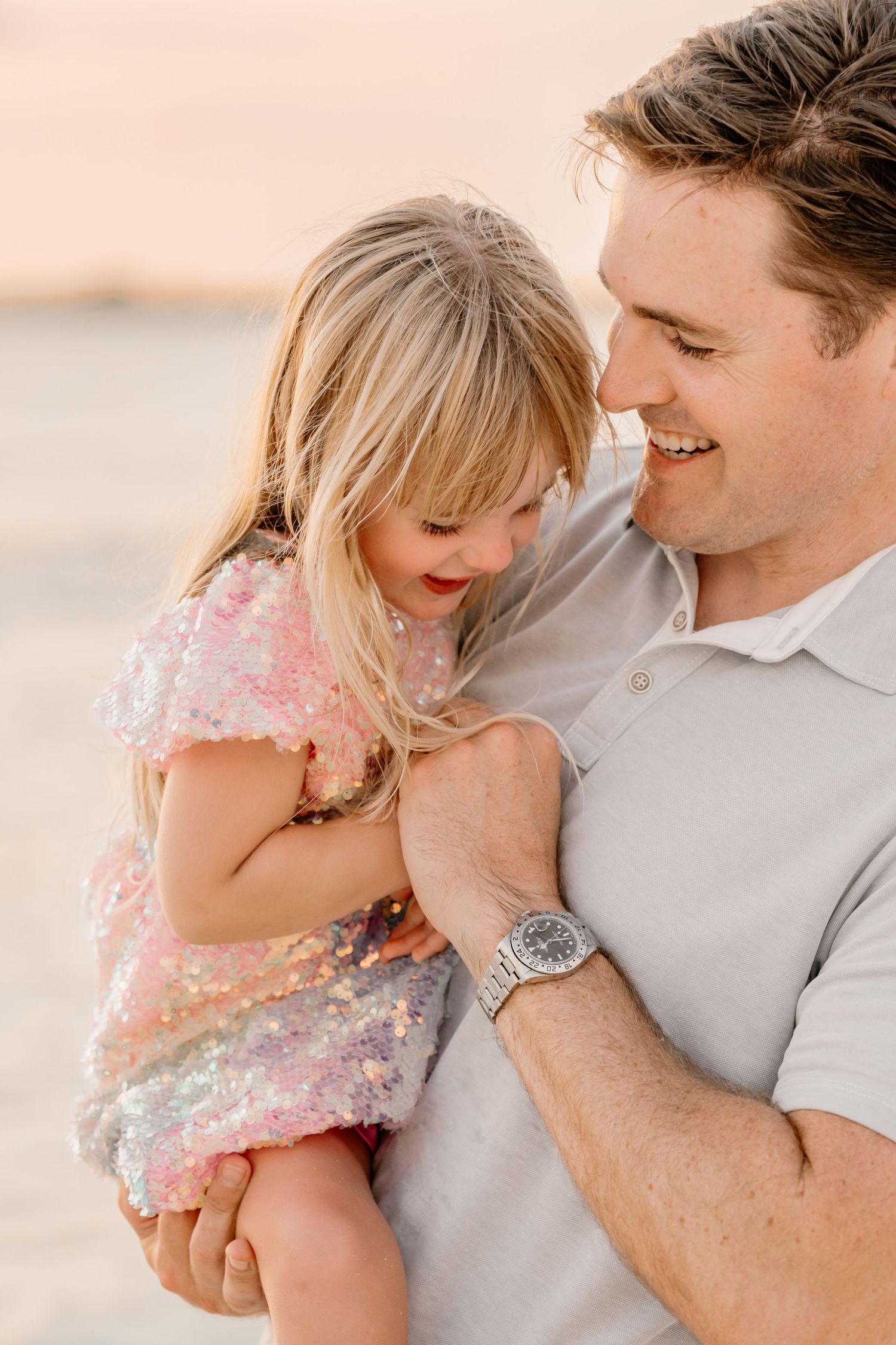 Tender beach moments captured in warm sunset lighting with sparkly details.