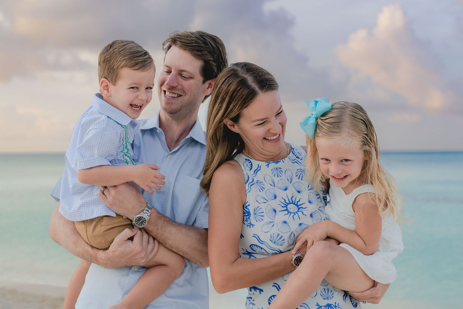 Family sharing tender moments together during sunset photo session on tropical beach.