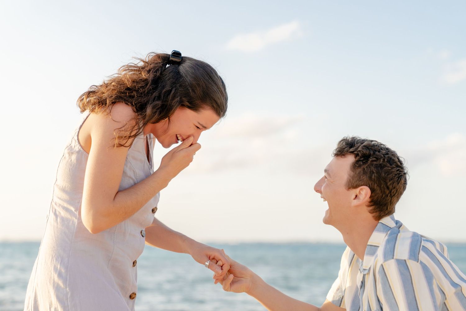 Couple sharing joyful moment on rocky beach during sunset.