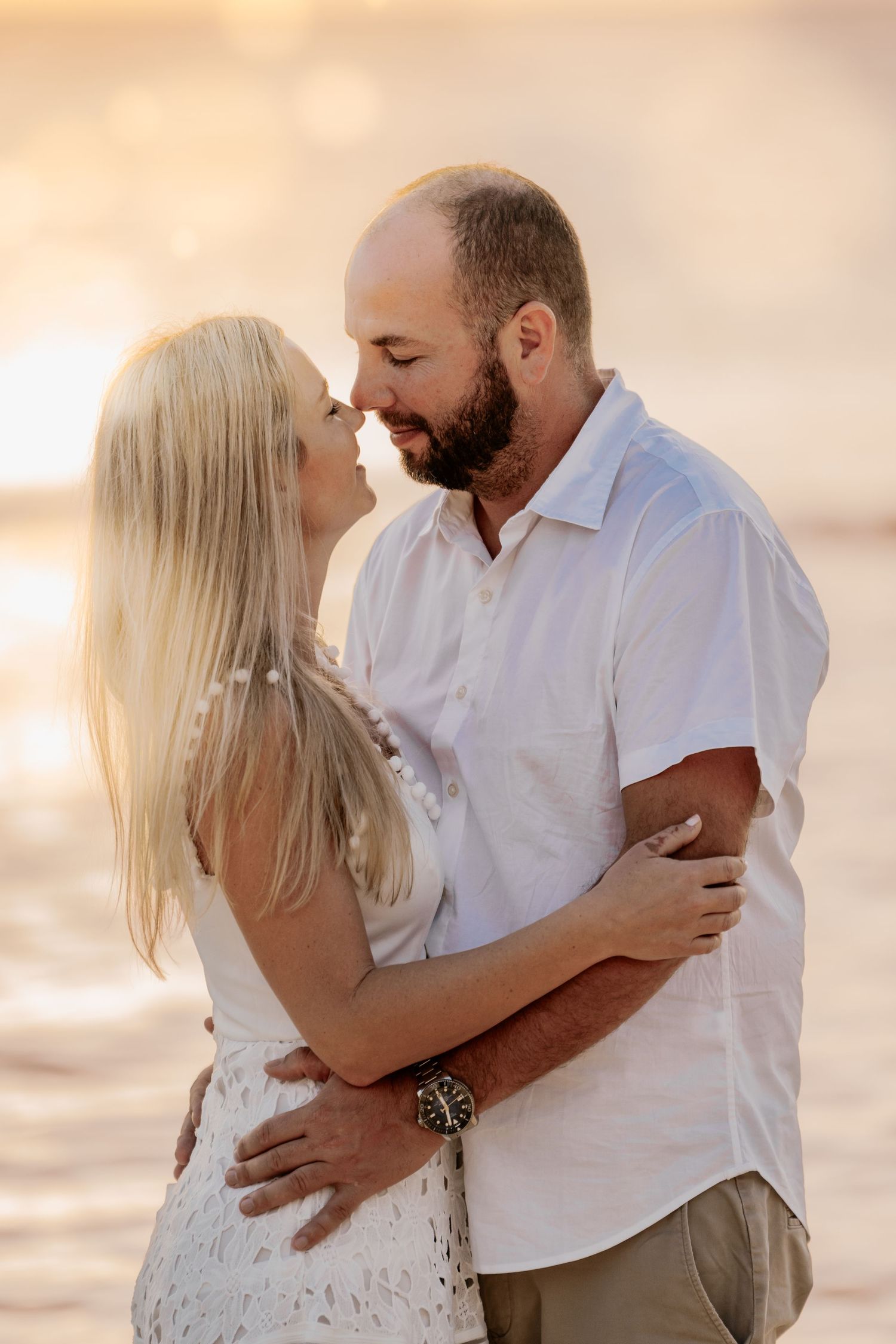 Sunset beach engagement session with warm golden light and soft pastel colors.