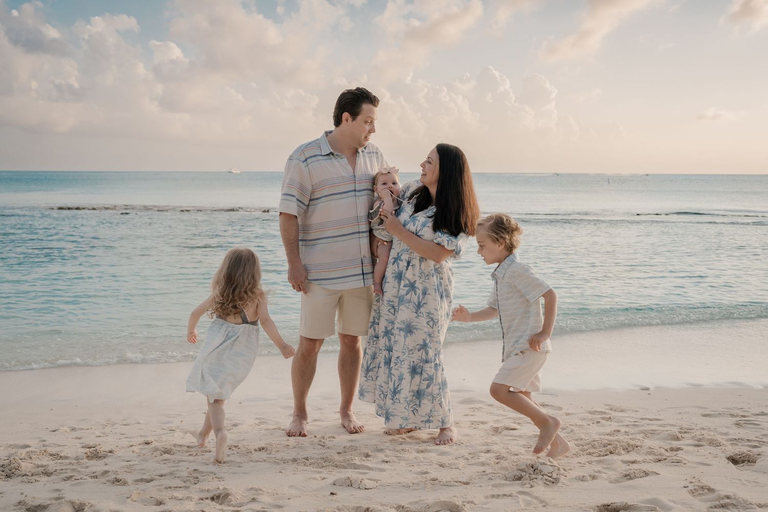 Playful interactions between loved ones on a serene beach during golden hour.