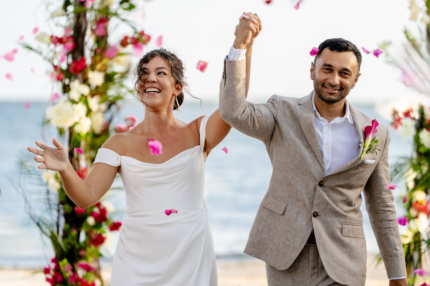 Wedding celebration with rose petals and joyful moments on a beach.