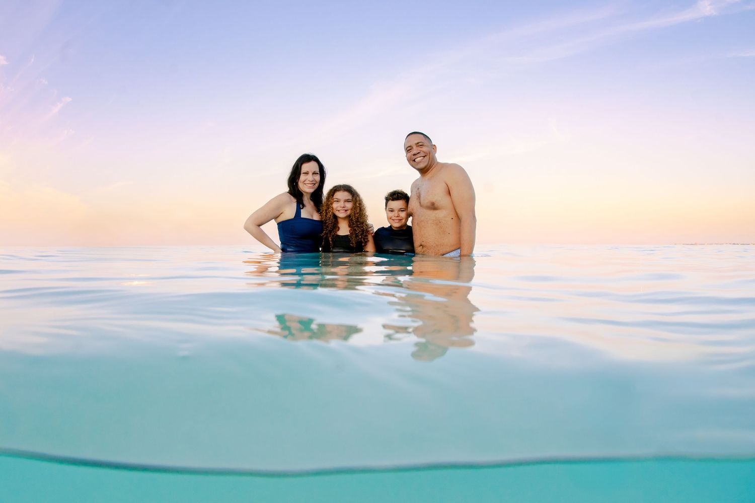 Family enjoying the crystal clear waters during a beach vacation photoshoot.