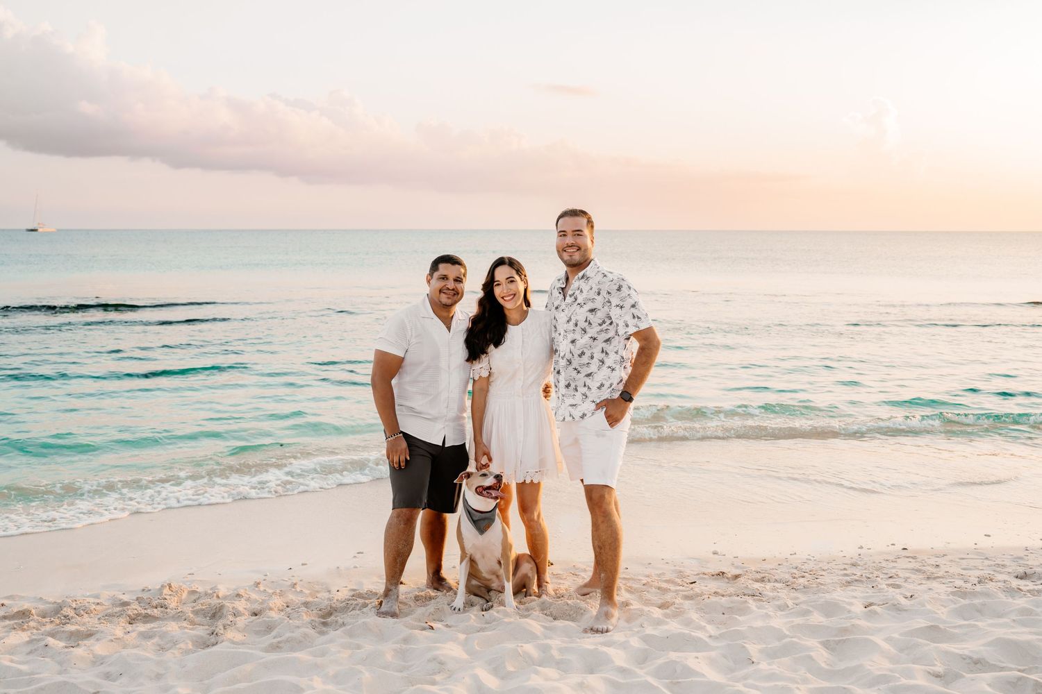 Group playing and laughing together on a sandy beach during golden hour with ocean waves behind them.