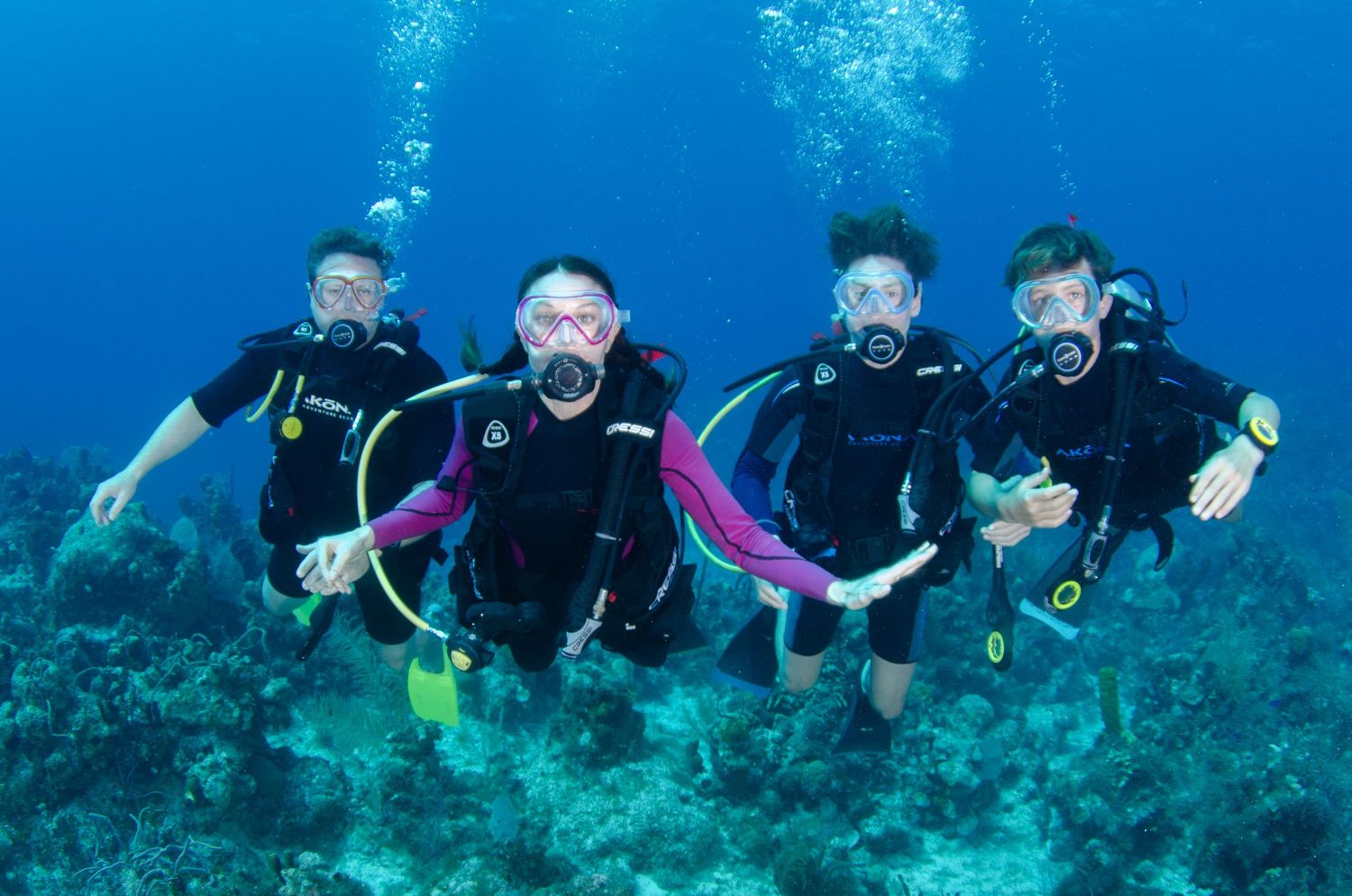 Group of scuba divers exploring vibrant coral reef in clear tropical waters.