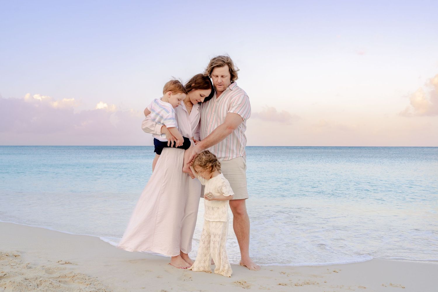 Romantic beach photoshoot at sunset with couple embracing on sandy shoreline.