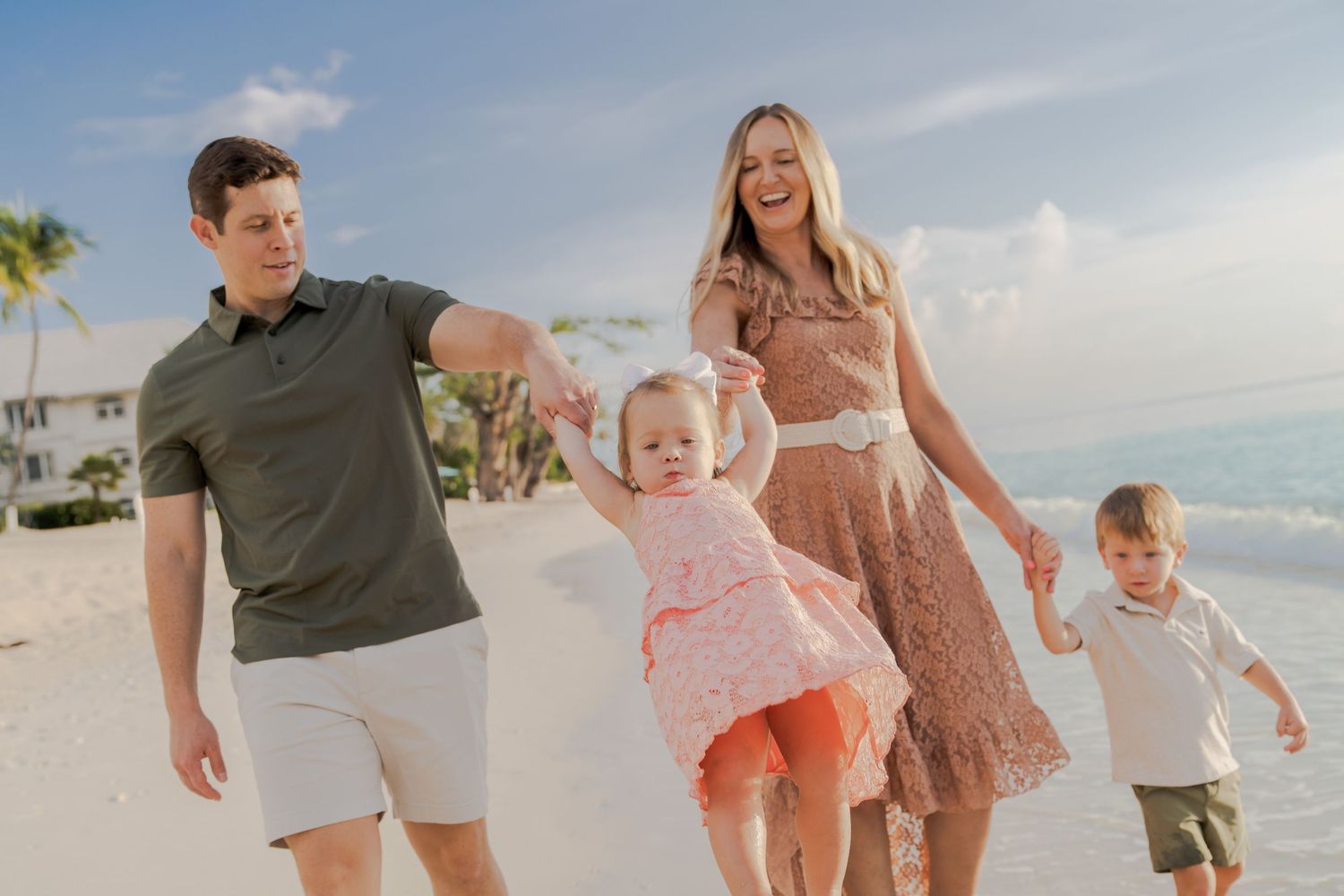 Joyful beach stroll with people wearing casual summer outfits along the shoreline at sunset.