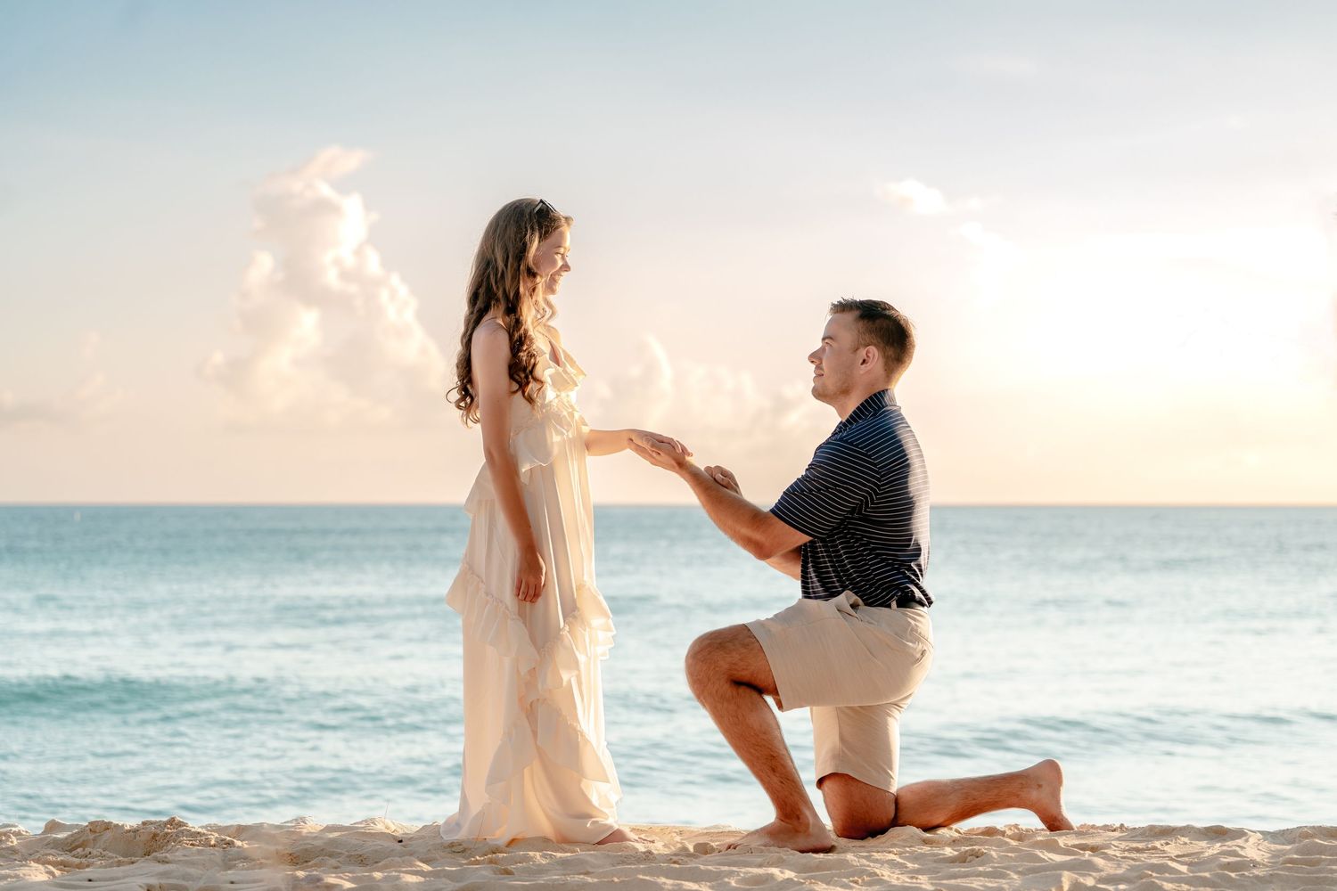 Surprise proposal moment captured on a tropical beach at sunset.