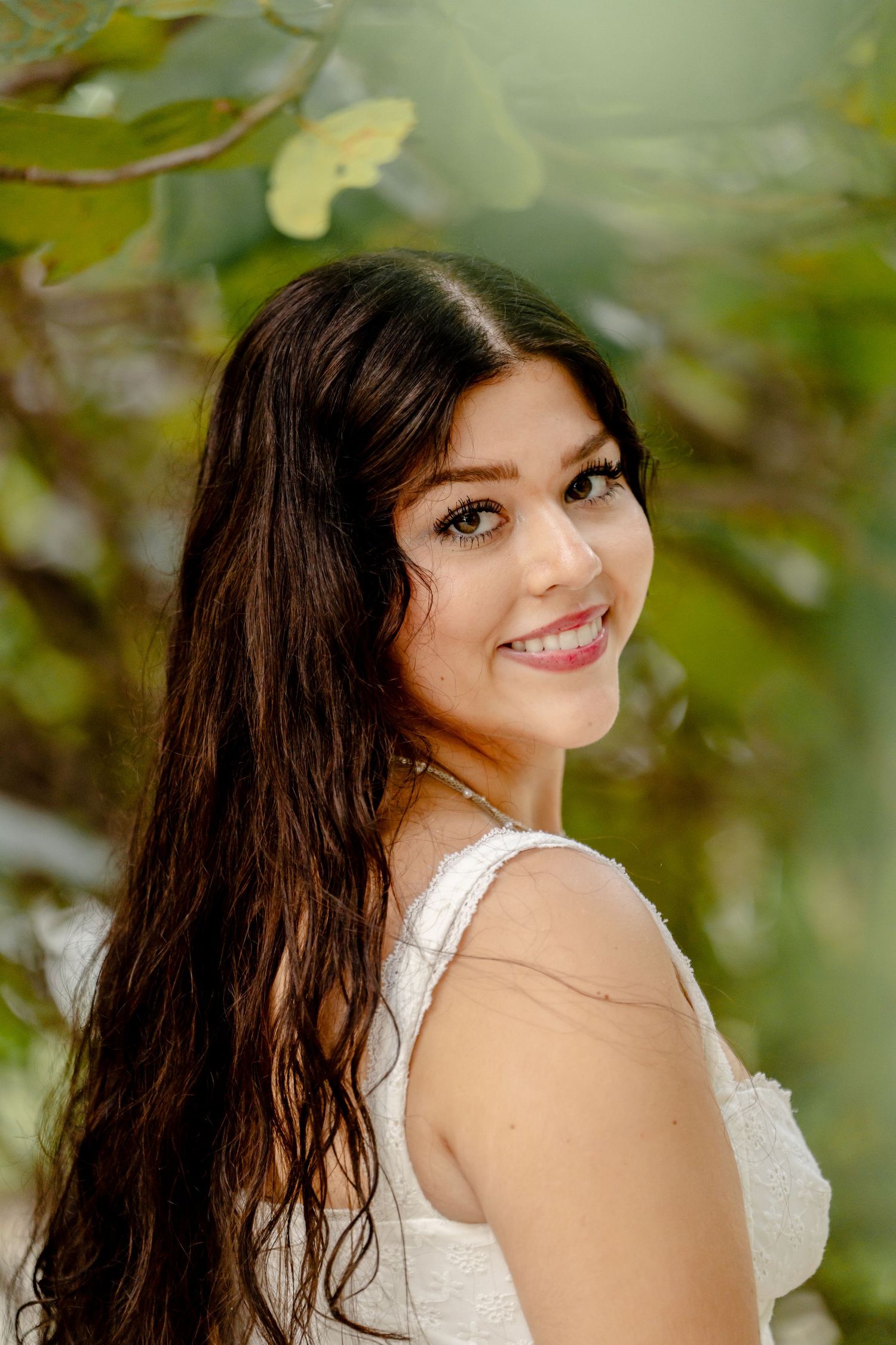 Radiant outdoor portraits with natural greenery backdrop and white dress.
