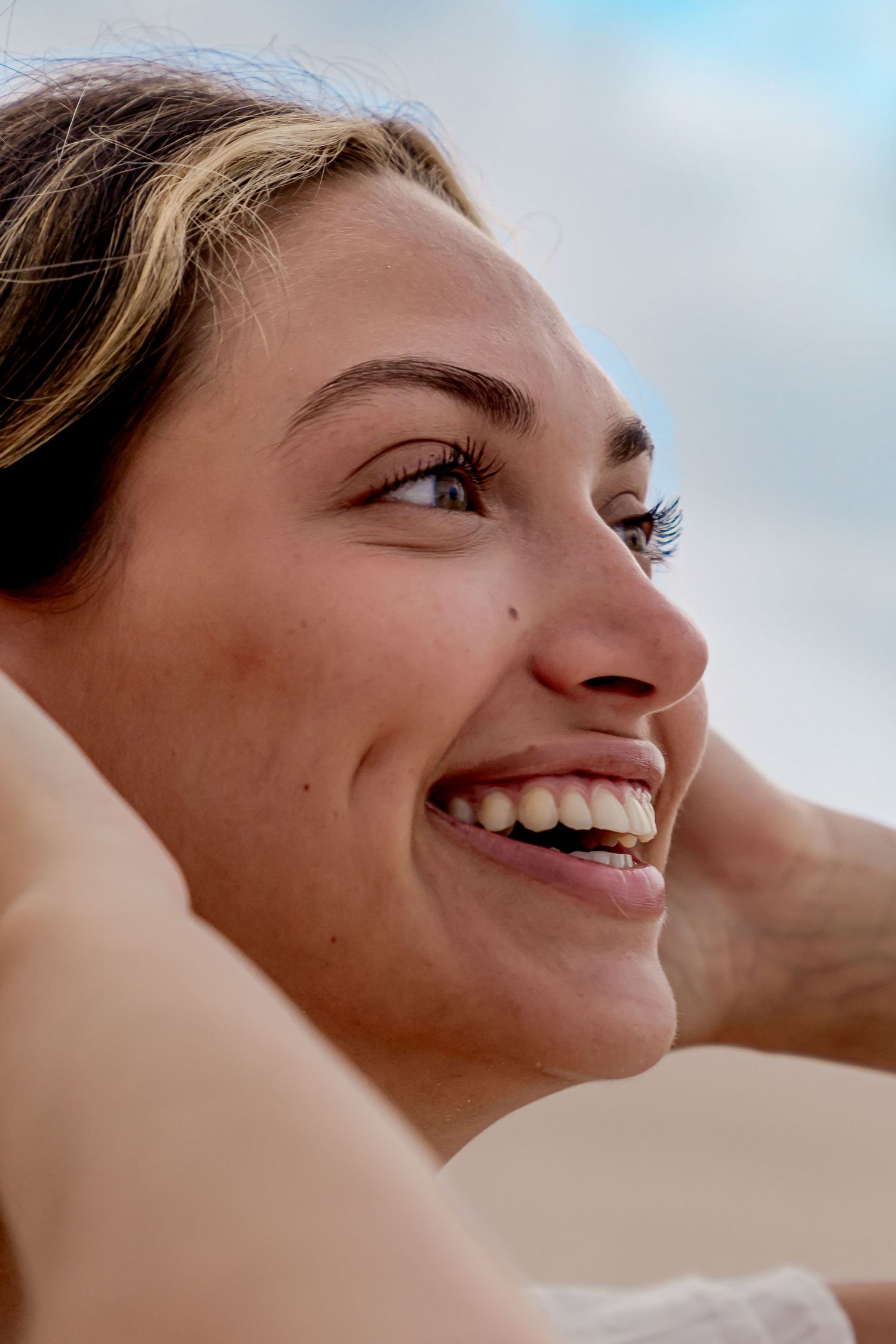 Close-up profile shot capturing joyful expressions against a bright sky background.