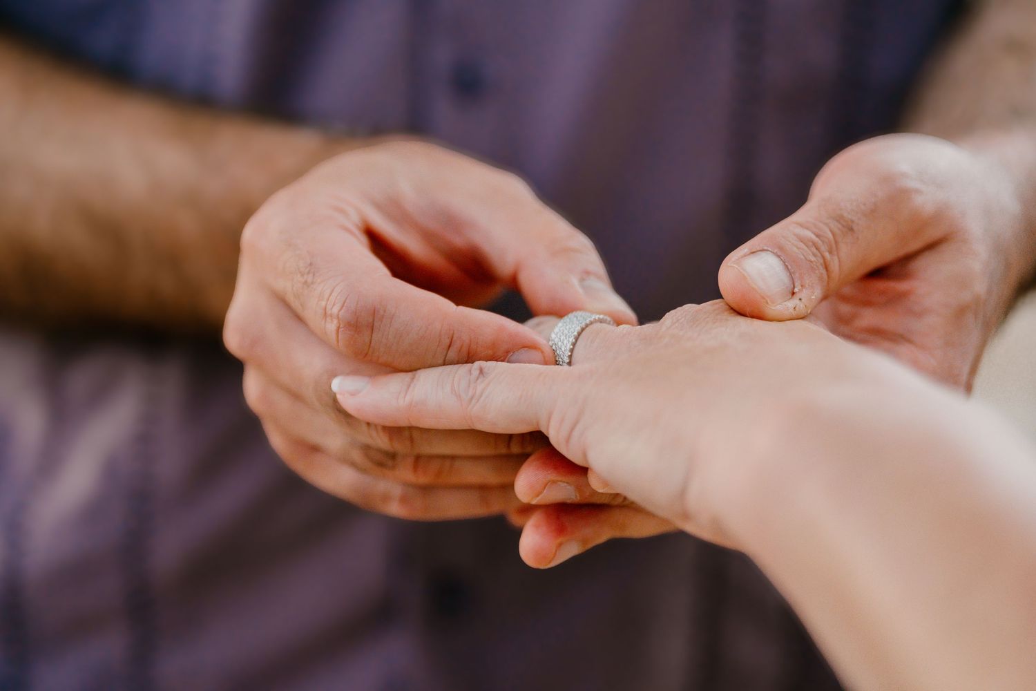 Close-up of hands exchanging rings during an intimate moment.