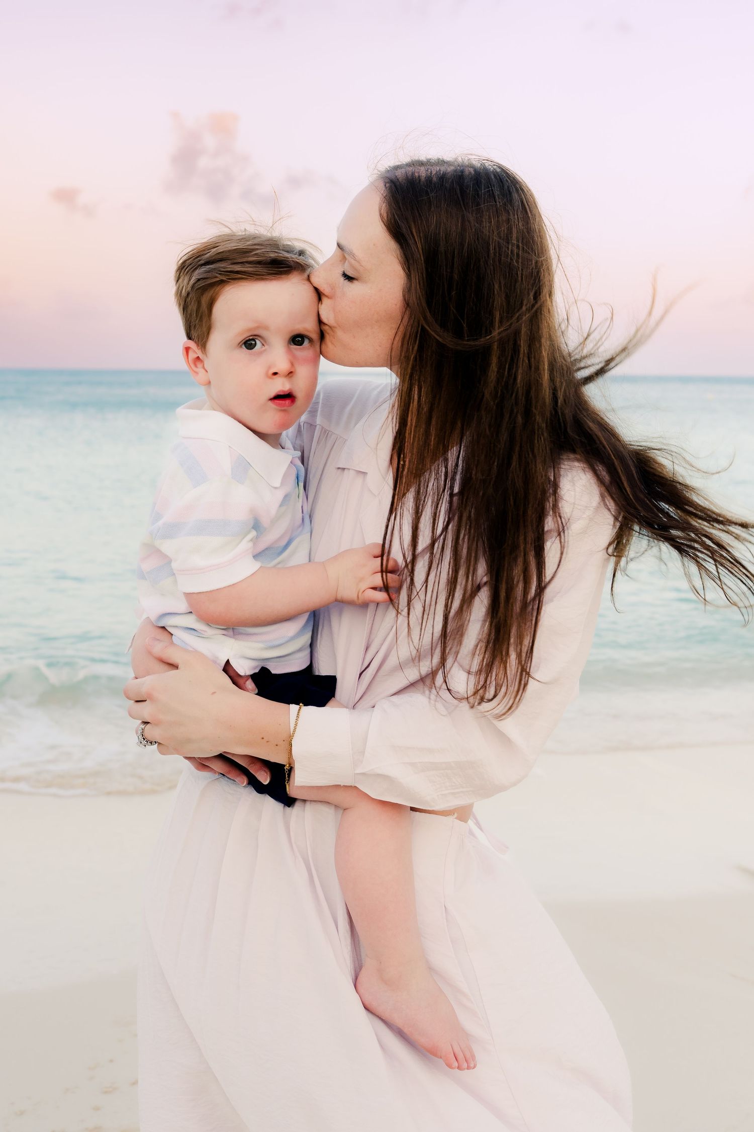Tender family moments captured during a beach photoshoot with soft sunset lighting.