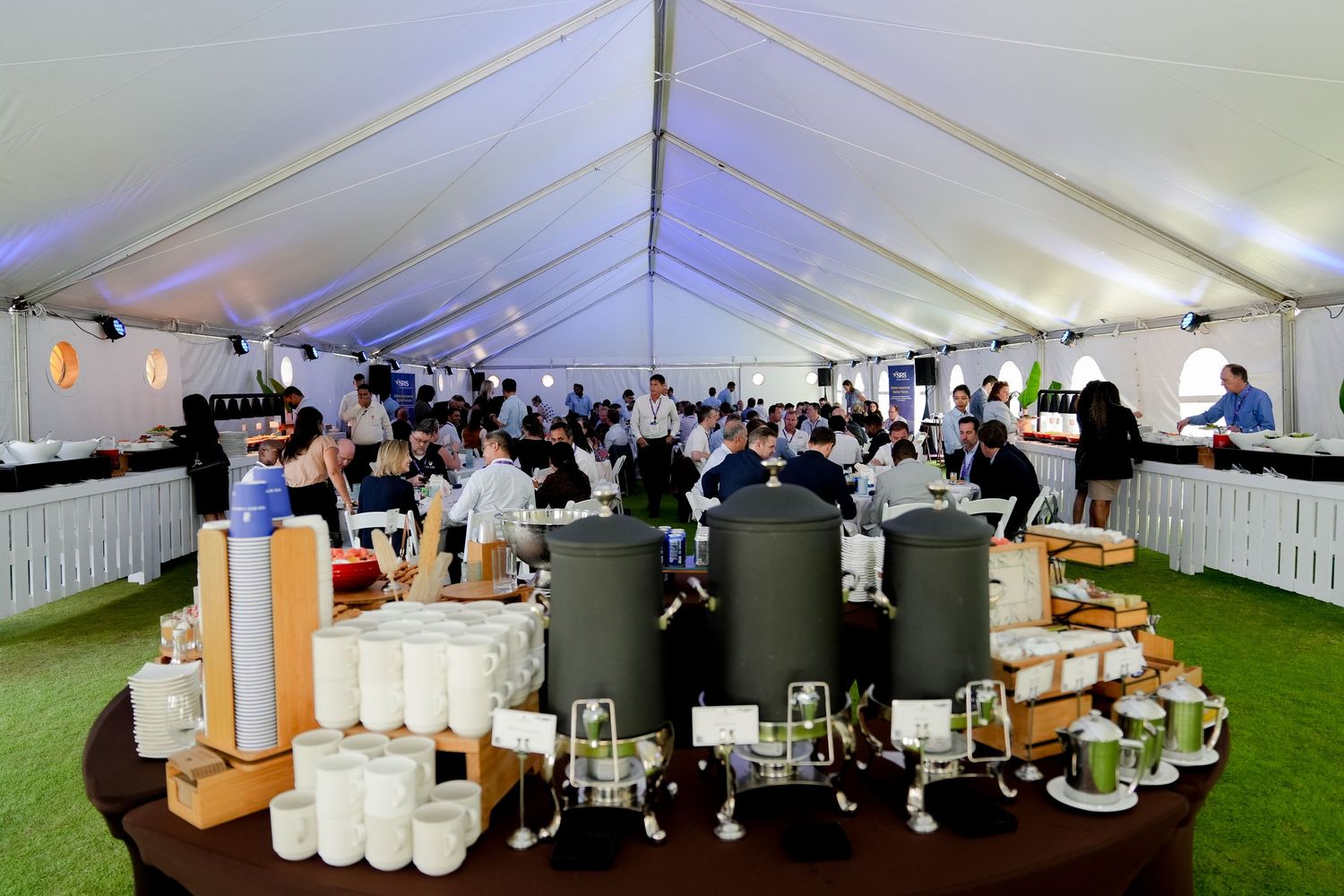 Large white event tent with tables and chairs set up for a conference or gathering.