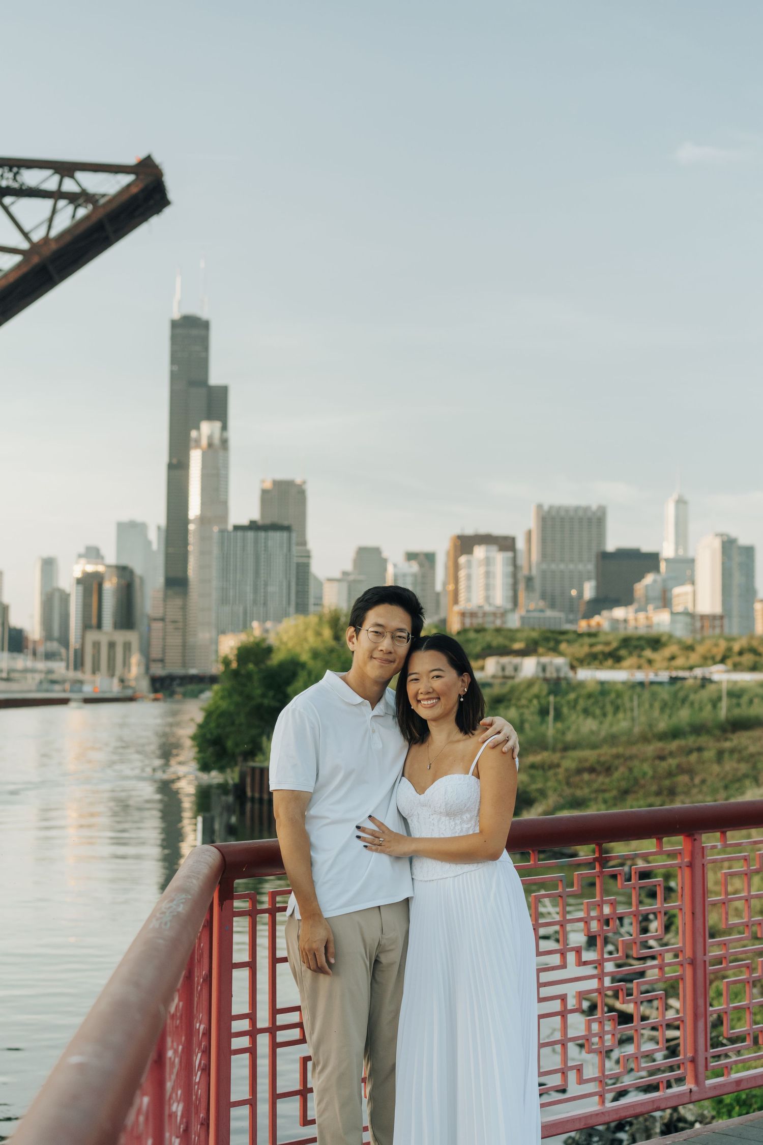 Couple posing on a bridge with Chicago skyline and Willis Tower in the background at golden hour.