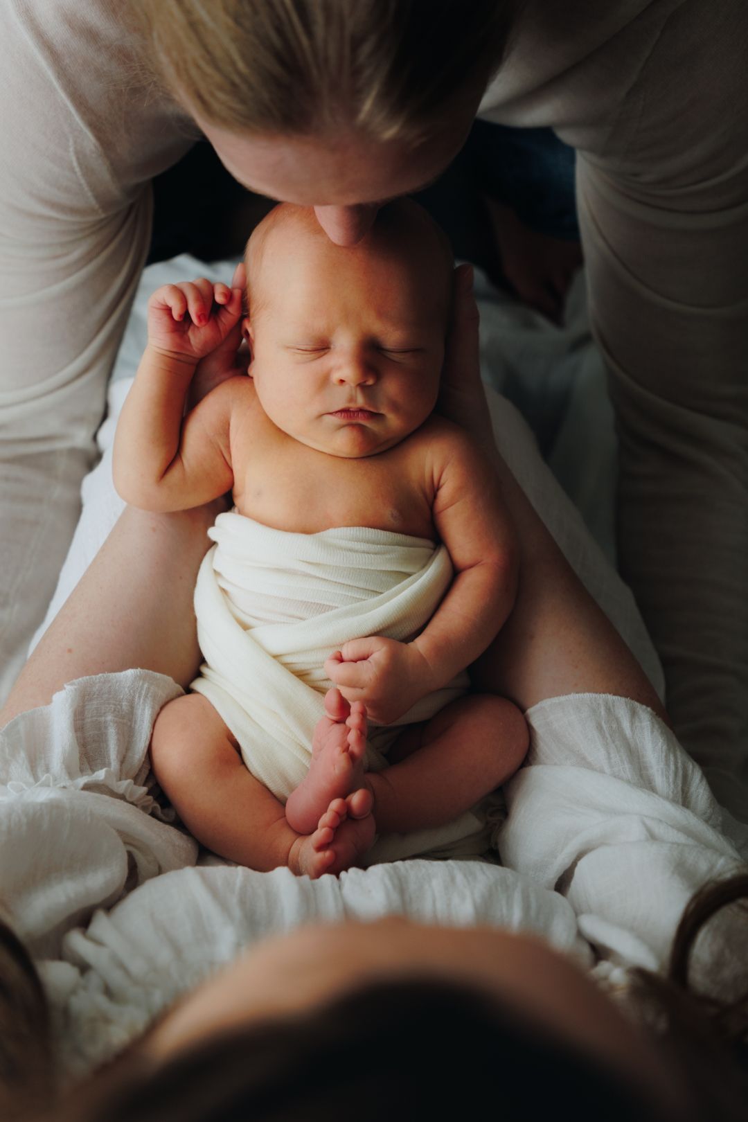 Close up views of a baby in a cloth diaper lying on soft white bedding, shown from different angles.