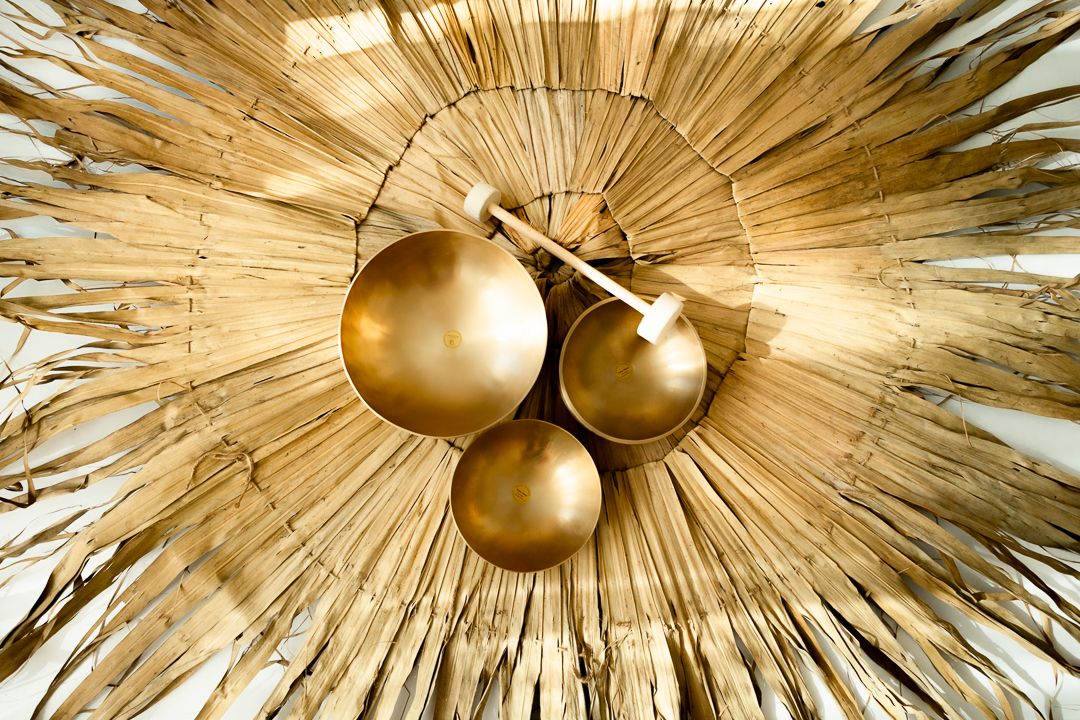 Gold sunburst wall art with three metallic spheres and radiating straw-like fringe in a decorative starburst pattern.